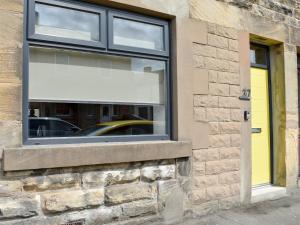 a window on a brick building with a yellow door at Hyem in Amble