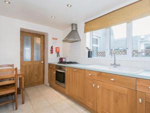 a kitchen with wooden cabinets and a sink and a window at Lazy Cottage in Haverigg