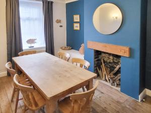 a dining room with a table and a fireplace at Lazy Cottage in Haverigg