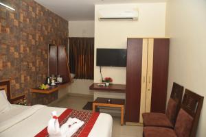 a hotel room with a bed and a chair at Hotel RD in Perundurai +12 photos