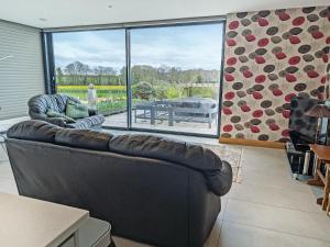 a living room with a leather couch and a large window at Park Barn in Whittington