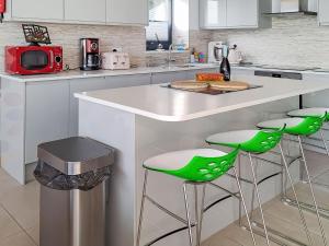 a kitchen with a counter with green bar stools at Park Barn in Whittington +14 photos