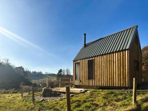 a wooden cabin with a metal roof on a field at Otter Gulley in Eddleston