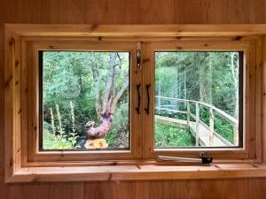 a window in a cabin with a view of a bird at Otter Gulley in Eddleston