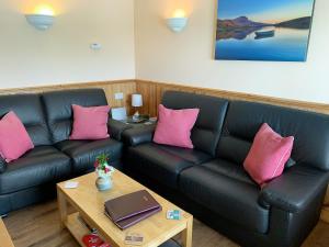 a living room with a black couch and pink pillows at Teenys Cottage in Flashader