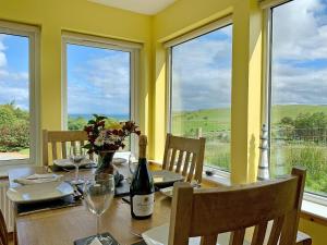 a dining room with a table with a bottle of wine at Teenys Cottage in Flashader