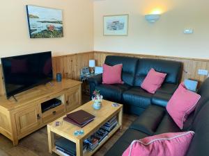 a living room with a couch and a flat screen tv at Teenys Cottage in Flashader