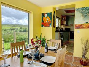 a dining room with a table with chairs and a window at Teenys Cottage in Flashader +6 photos