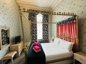 ein Schlafzimmer mit Himmelbett und einem rosa Stofftier in der Unterkunft Eliza House in Edinburgh