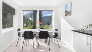 a white dining room with a white table and black chairs at Kvitefjell 35 in Loen