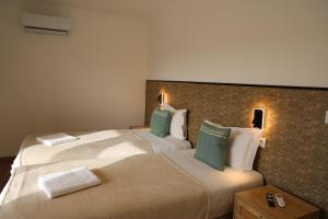 two beds in a hotel room with green pillows at Olivale Villas in Campo Maior +18 photos