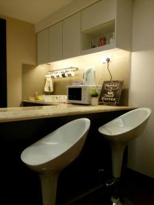 a kitchen with two white stools in front of a counter at Dar Es Salam in Kota Bharu