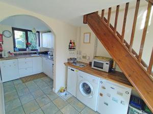 a kitchen with a washing machine and a staircase at White Cottage in Hemingby +6 photos