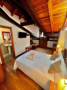 a large white bed in a room with wooden ceilings at Hotel Rural El Sestil in Dobres