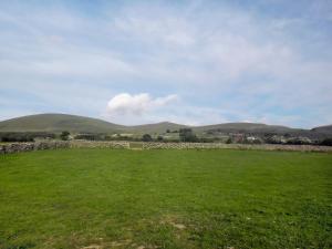 a field with a stone wall and mountains in the background at Y Gorlan - Uk6403 in Llanllechid +1 photo