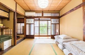 a room with three beds and a large window at Guest House Hitsujian in Kyoto