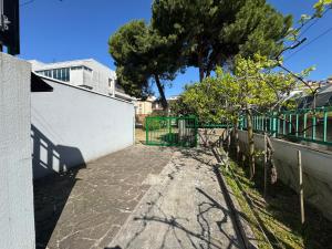 a driveway with a green gate and a tree at Villa Terme in Grado