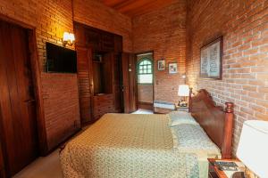 a bedroom with a bed and a brick wall at Estalagem Entardecer da Serra in Monte Verde