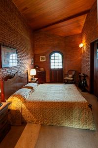 a bedroom with a bed and a brick wall at Estalagem Entardecer da Serra in Monte Verde