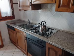 a kitchen with a stove with a tea kettle on it at B&B Casa Orchidea in Baragazza