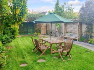 a wooden table and chairs with an umbrella in a yard at Awel-Y-Mor in Aberaeron