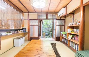 a room with a wooden table and bookshelves at Guest House Hitsujian in Kyoto