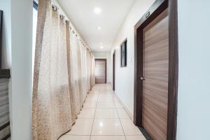 a hallway with a wooden door and a corridor with white walls at FabHotel Garden Tree in Bhubaneshwar