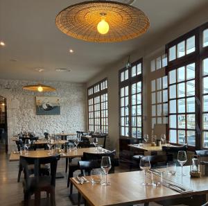 a restaurant with wooden tables and chairs and windows at Les Bains Boyardville - Hôtel et Restaurant in Boyard-Ville