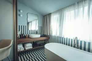 ein Badezimmer mit Badewanne, Waschbecken und Spiegel in der Unterkunft Boutique Hotel Villa Alberta in Nago-Torbole