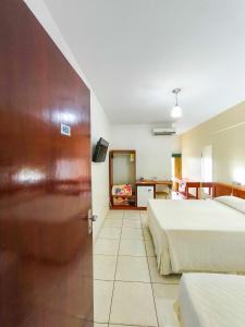 a hotel room with two beds and a door at Foz Presidente Economic Hotel in Foz do Iguaçu +105 photos