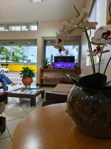 a living room with a vase with flowers on a table at Foz Presidente Economic Hotel in Foz do Iguaçu