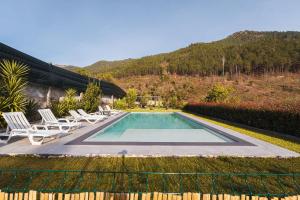 a swimming pool with chairs and a house at Gerês Home Nature in Geres