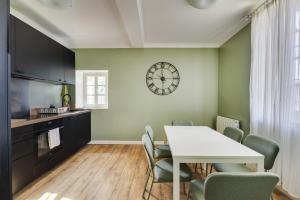 a kitchen with a table and chairs and a clock on the wall at L'Estanquet - Maison d'Hôtes in Gardouch