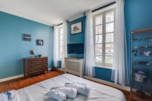 a bedroom with blue walls and a bed and a window at L'Estanquet - Maison d'Hôtes in Gardouch