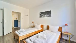 two beds in a room with white walls at Spacious Flat 2nd Floor near station in Karlsruhe