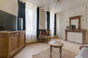 a living room with a flat screen tv and a table at Secret de Briques - classé 4 étoiles in Vigneux-Hocquet