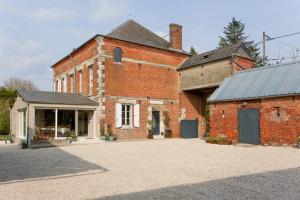 an old brick building with a garage in front of it at Secret de Briques - classé 4 étoiles in Vigneux-Hocquet