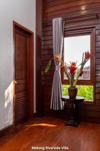 a window with a vase on a table next to a window at Mekong Riverside Villa in Vientiane