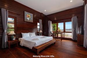 a bedroom with a bed with wooden walls and windows at Mekong Riverside Villa in Vientiane