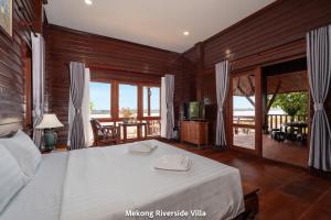 a bedroom with a large bed and a balcony at Mekong Riverside Villa in Vientiane