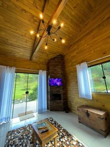 a living room with a wooden ceiling with a tv at Refúgio do Vale Estalagem in Annitapolis