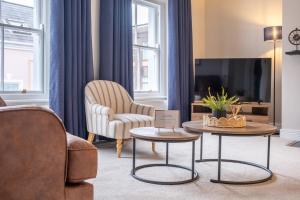 a living room with a couch and a chair and tables at Pump House Apartments in Derry Londonderry