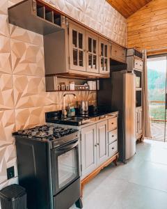 a kitchen with a stove and a refrigerator at Refúgio do Vale Estalagem in Annitapolis