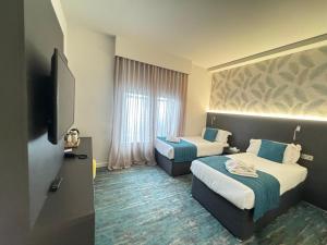 a hotel room with two beds and a flat screen tv at K Hotel Kensington in London