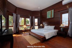 a bedroom with a bed with wooden walls and windows at Mekong Riverside Villa in Vientiane
