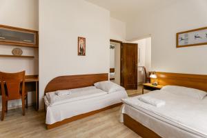 a hotel room with two beds and a desk at Vila Vyšehrad in Luhačovice