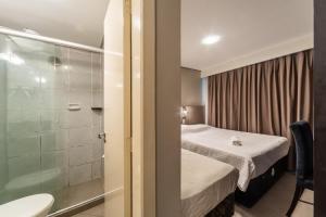 ein kleines Schlafzimmer mit Bett und Dusche in der Unterkunft Minuano Hotel Express próx Orla Lago Guaíba, Mercado Público, 300 m Rodoviária in Porto Alegre
