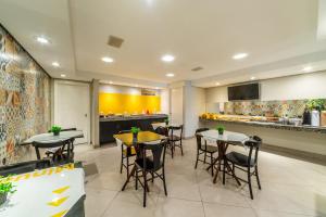 ein Restaurant mit Tischen und Stühlen und einer Küche in der Unterkunft Minuano Hotel Express próx Orla Lago Guaíba, Mercado Público, 300 m Rodoviária in Porto Alegre