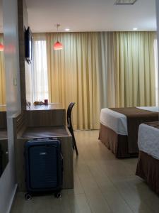 a hotel room with a bed and a suitcase at Foz Presidente Comfort Hotel in Foz do Iguaçu