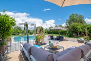 a patio with couches and a swimming pool with an umbrella at Villa Lavinia in Alghero